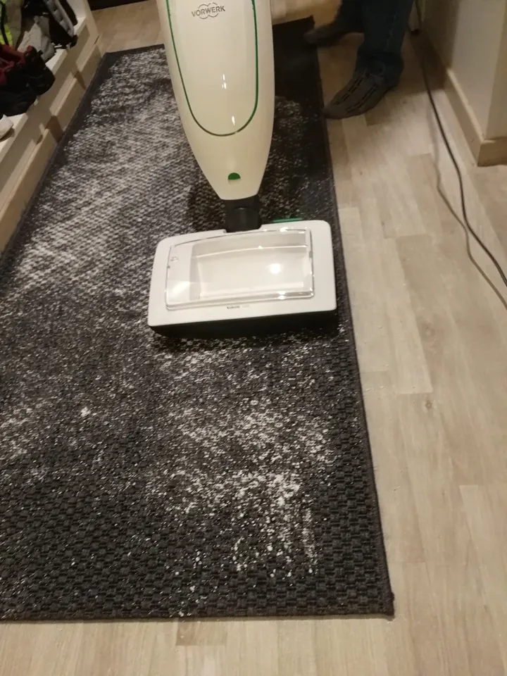 Kuivapesuaine levitettyn&auml; matolle ja Vorwerk-pesulaite ty&ouml;ss&auml;